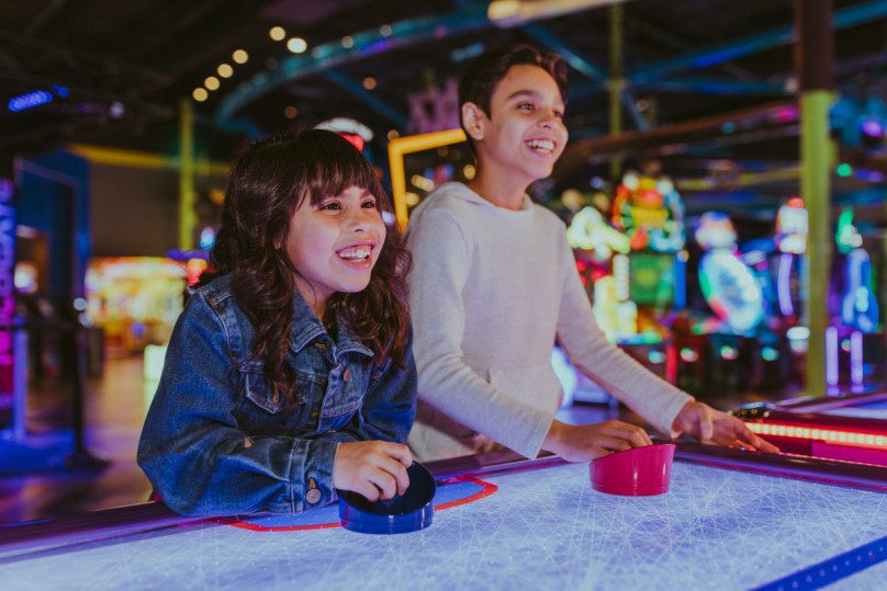 Two children playing air hockey in an arcade during a field trip in Zap Zone