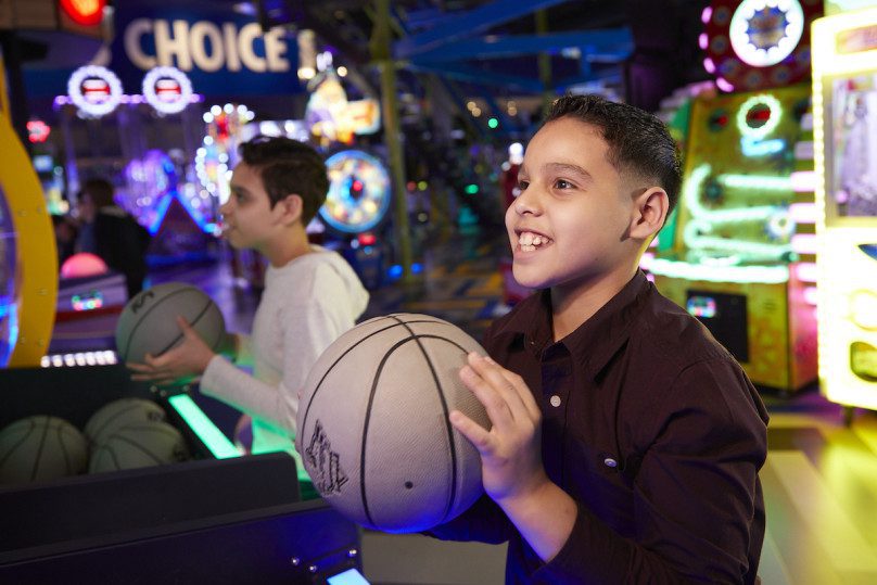 A boy holding a basketball in an arcade during a field trip in Zap Zone